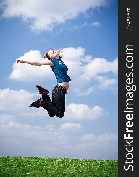 The happy jumping girl on a background of the blue sky