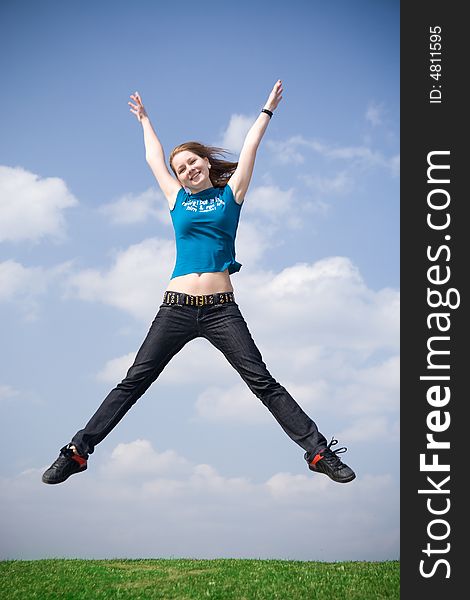 The happy jumping girl on a background of the blue sky