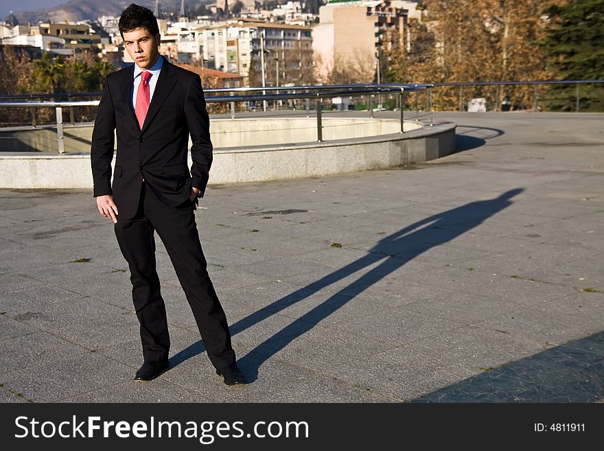 Standing businessman posing on city background