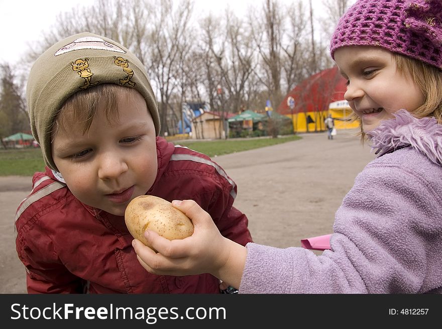 Playful girl feeds a boy with potato. Playful girl feeds a boy with potato