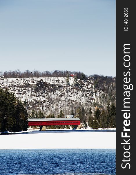 Red covered bridge over the water and in the forest