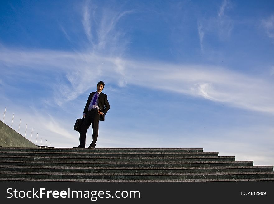 Businessman posing on stairs against blue sky. Businessman posing on stairs against blue sky.