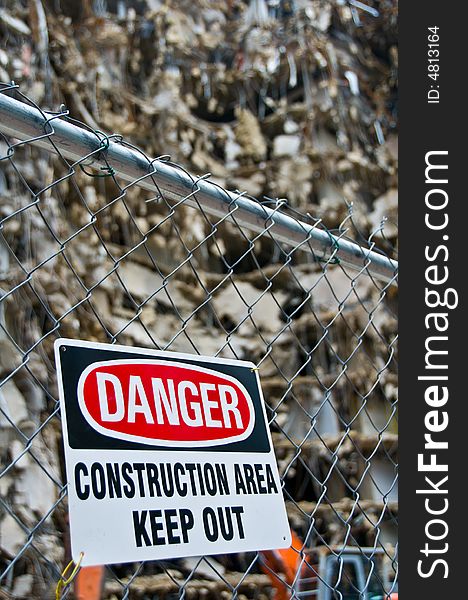 Warning sign posted on fence around massive demolition project, shallow depth of field - part of series. Warning sign posted on fence around massive demolition project, shallow depth of field - part of series