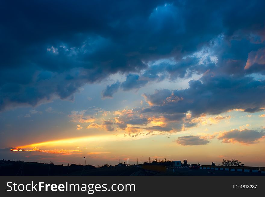 Colorful sunset with clouds and sunbeams over rural skyline. Colorful sunset with clouds and sunbeams over rural skyline