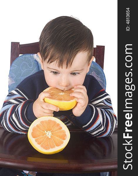 Small boy eats fresh grapefruit isolated on white background
