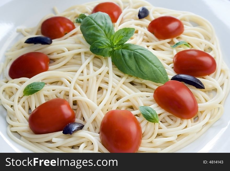 Close up of a spaghetti dish with cherry tomatoes, black olives and basil. Close up of a spaghetti dish with cherry tomatoes, black olives and basil.