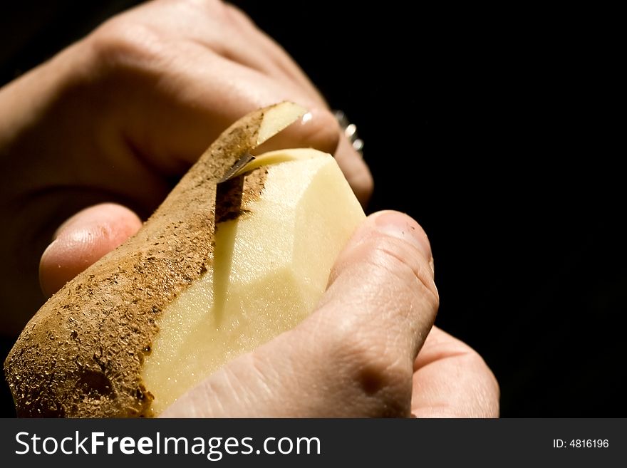 A women peeling a potato close up of the womens hands