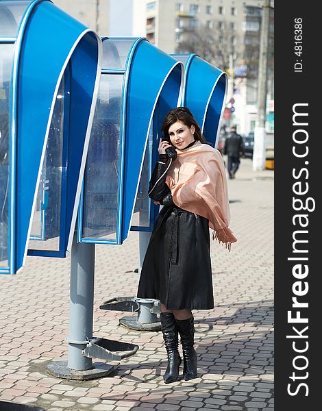 An image of a girl speaking on public telephone. An image of a girl speaking on public telephone