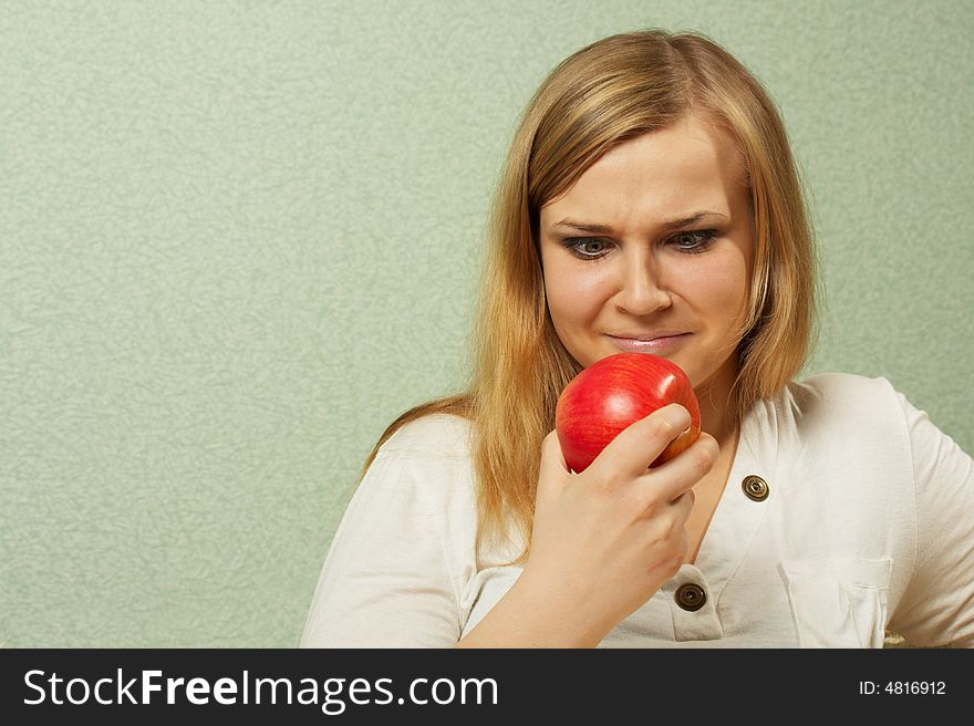 The dissatisfied girl looks at a red apple. The dissatisfied girl looks at a red apple