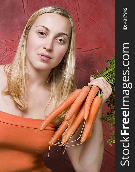 Young beautiful woman with the bunch of carrots. Young beautiful woman with the bunch of carrots