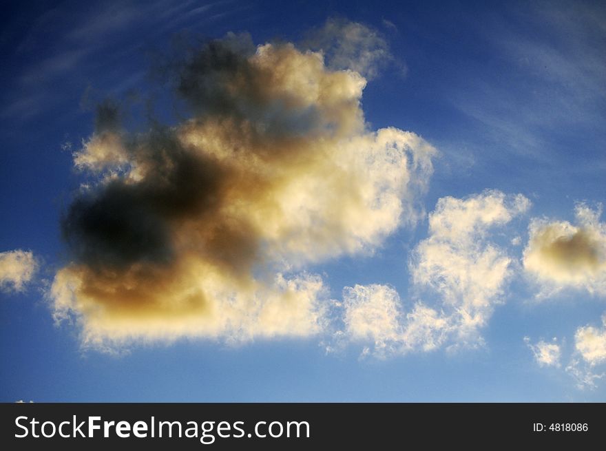 Some puffy tawny clouds over a deep blue sky at sunset