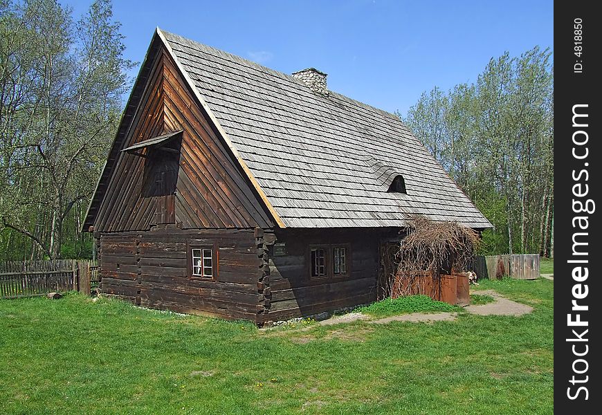 Old wooden hut in village, green grass around