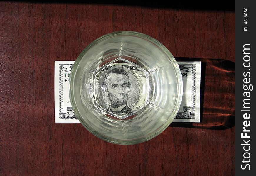 Banknote of $5 under transparent wisky glass. Banknote of $5 under transparent wisky glass