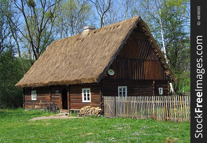 Old wooden hut in village, green grass around