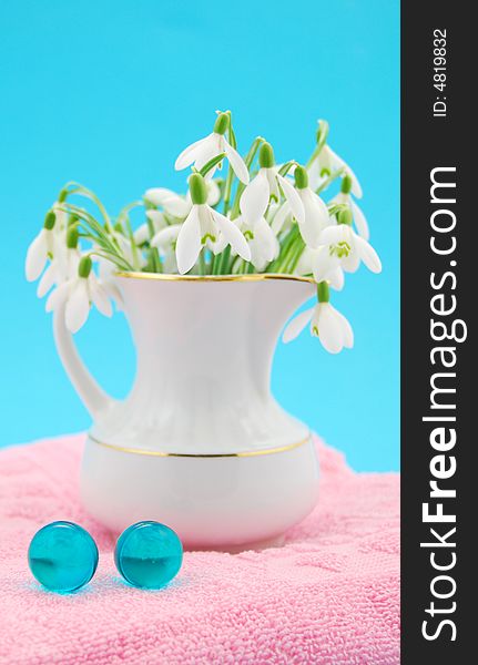 Bath oil and spring flowers in porcelain vase on blue background. Bath oil and spring flowers in porcelain vase on blue background