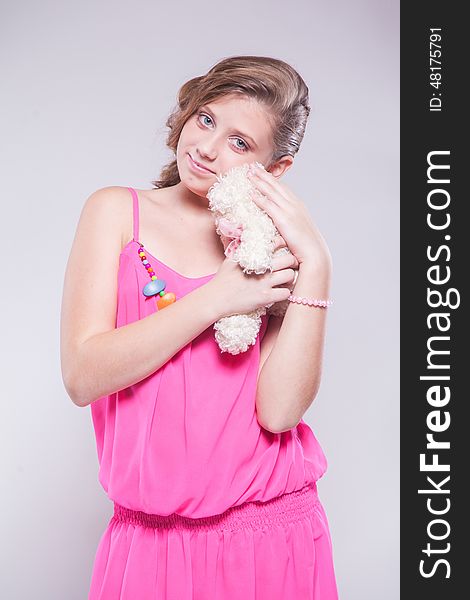 Girl in a pink dress holding a teddy bear and smiling
