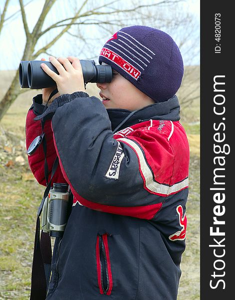 The boy of ten years observes into the binoculars nature or plays into the game with other children. The boy of ten years observes into the binoculars nature or plays into the game with other children