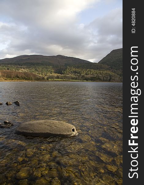 Rock in a clear water lake with mountains in the background. Rock in a clear water lake with mountains in the background