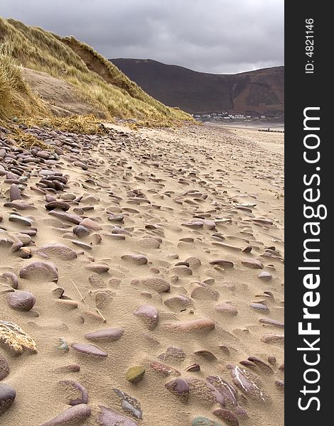 Sandy beach with sand dunes and pebbles covered by sand in the wind. Sandy beach with sand dunes and pebbles covered by sand in the wind