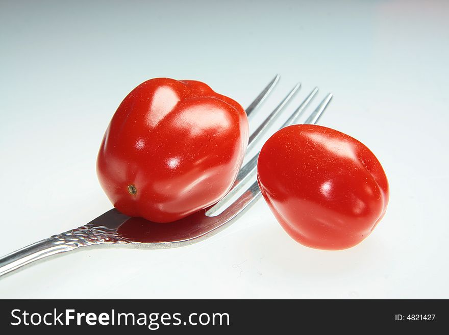 Small, red tomatoes and fork. Small, red tomatoes and fork