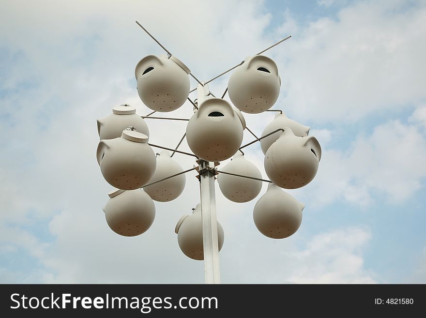 White birdhouses against a blue sky background with white clouds. White birdhouses against a blue sky background with white clouds