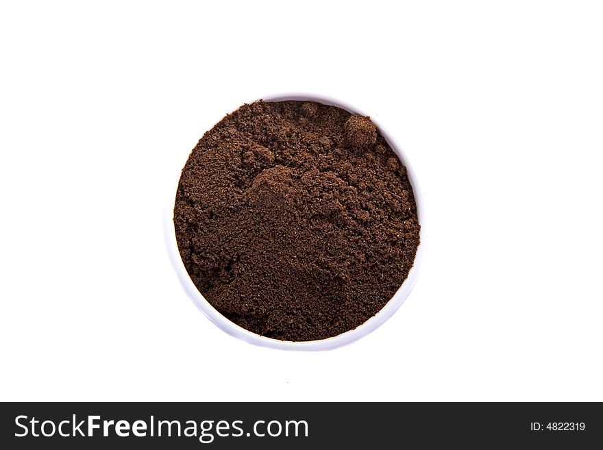 A white cup filled with freshly ground coffee beans on a white background. A white cup filled with freshly ground coffee beans on a white background