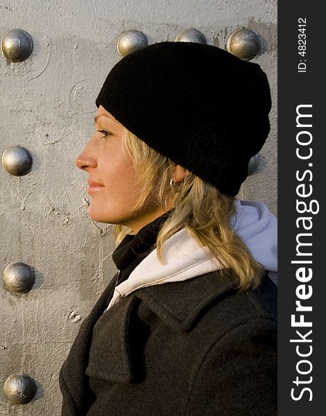 Portrait of the blonde in a cap on a background of a silvery wall. Portrait of the blonde in a cap on a background of a silvery wall