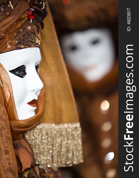 White mask with a brown costume at the Venice Carnival. White mask with a brown costume at the Venice Carnival