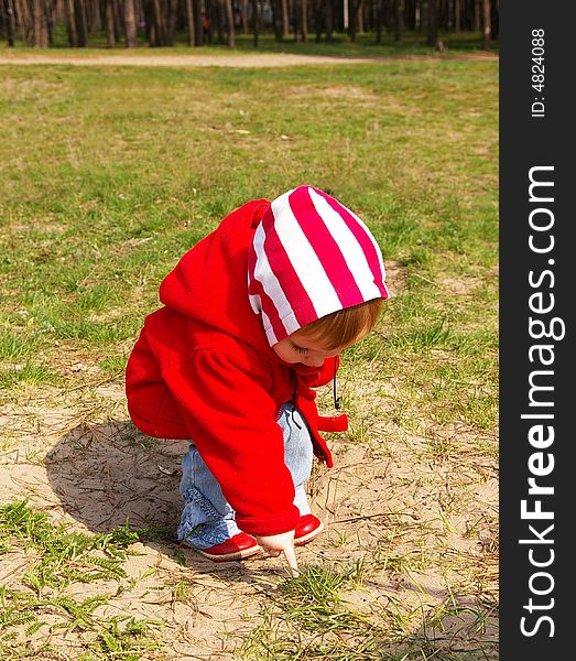 Little girl in a wood looks at a grass