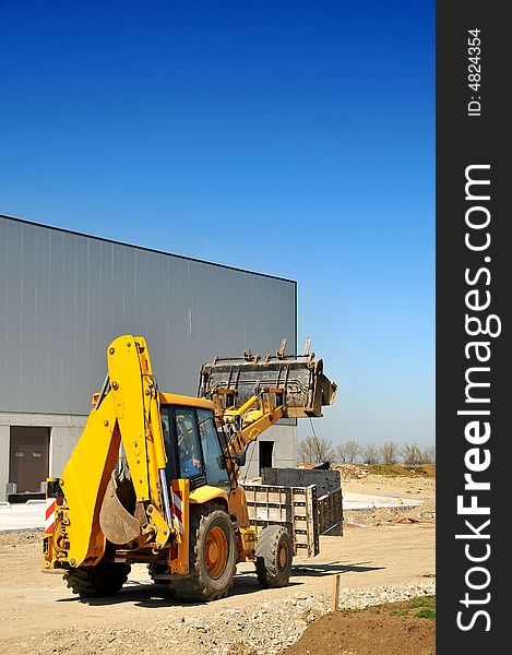 Yellow backhoe loader on construction site- side view