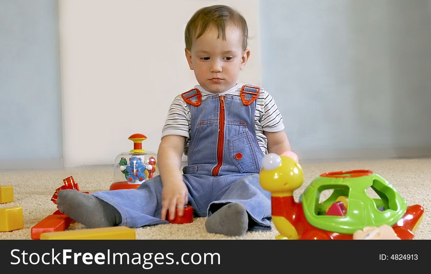 Sad baby boy with toys