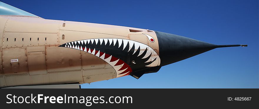 An F-105G Thunderchief fighter aircraft stands out dramatically against a clear blue sky