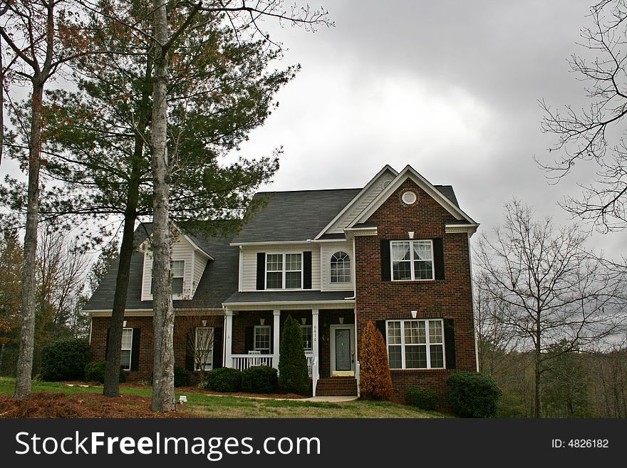 Large expensive brick home with dormer window and a landscaped yard.