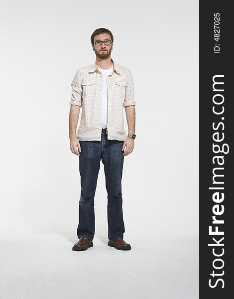 Full length photo of man a with beard standing inside a photostudio. Hewearing a creame pattern shirt and denim jeans. Full length photo of man a with beard standing inside a photostudio. Hewearing a creame pattern shirt and denim jeans.
