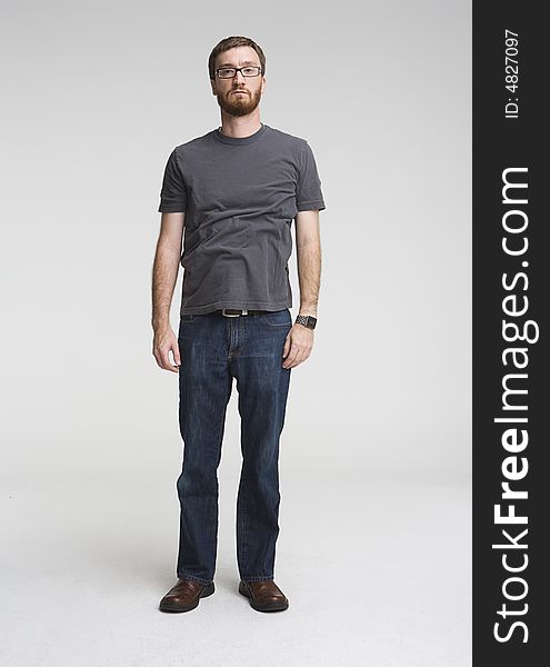 Full length photo of man a with beard standing inside a photostudio. His shirt is entirely wrinkled and he has serious expression on his face. Full length photo of man a with beard standing inside a photostudio. His shirt is entirely wrinkled and he has serious expression on his face.