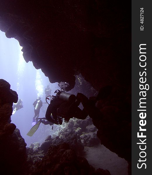 Dark cavern with divers swimming out