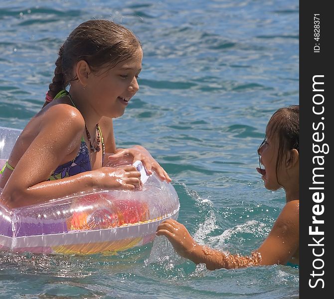 Two girls of teenager bath in a sea on a rubber circle. Two girls of teenager bath in a sea on a rubber circle