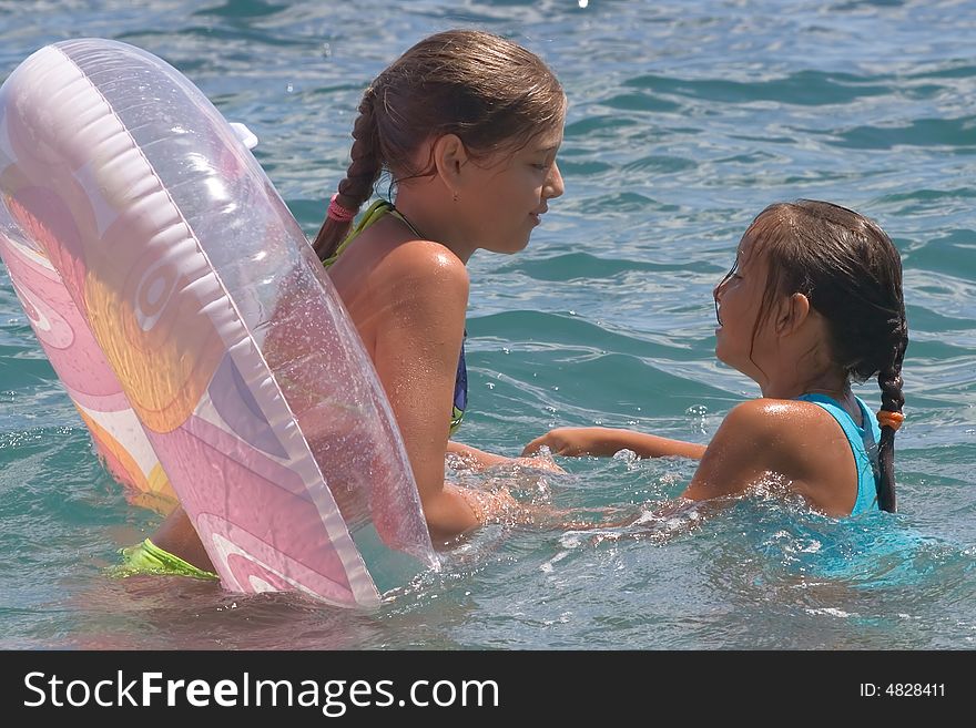 Two girls of teenager bath in a sea on a rubber circle. Two girls of teenager bath in a sea on a rubber circle