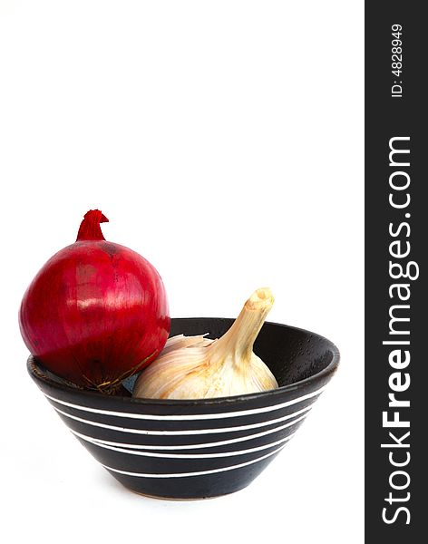 Red onion and garlic in a black bowl with white pattern