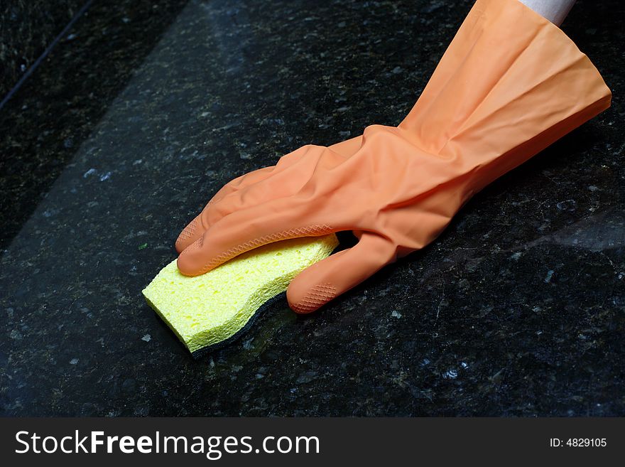 A person cleaning the Kitchen Counter with a glove. A person cleaning the Kitchen Counter with a glove