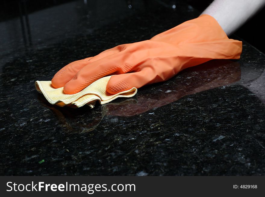 A person cleaning the Kitchen Counter with a glove. A person cleaning the Kitchen Counter with a glove