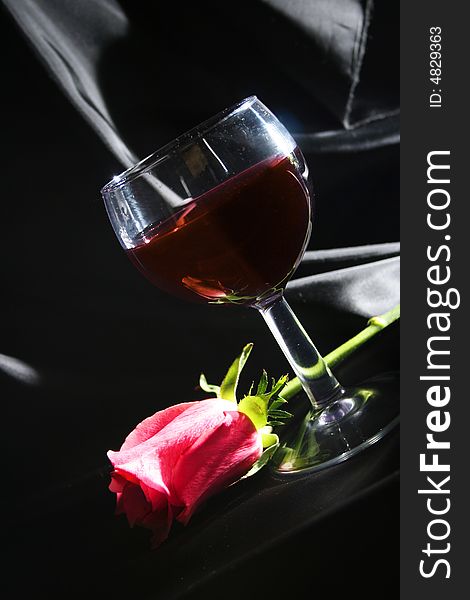 Red wine and rose on black background. Red wine and rose on black background