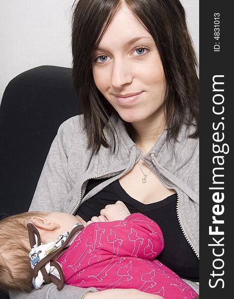 Young mother on a sofa with their baby girl. Young mother on a sofa with their baby girl