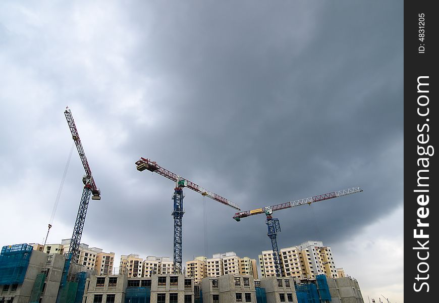 Cranes at rest at a construction site as a tropical convectional storm set to break. Cranes at rest at a construction site as a tropical convectional storm set to break