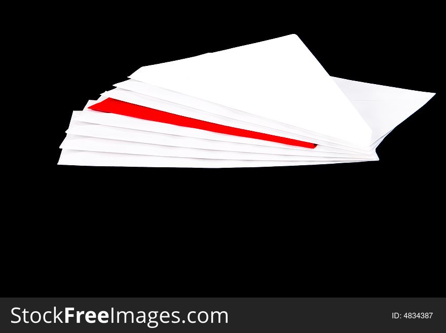 Red envelope in a pile of white envelopes with a black background. Red envelope in a pile of white envelopes with a black background