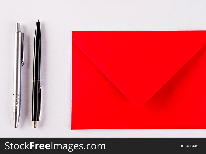 Two pens and a red envelope on a white background