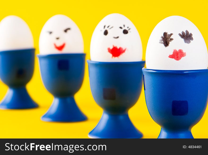 Painted children's eggs in blue egg cups. Painted children's eggs in blue egg cups