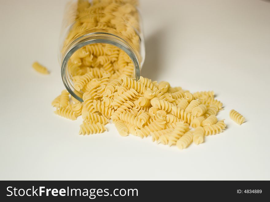 Italian fusilli pasta falling out of a glass jar