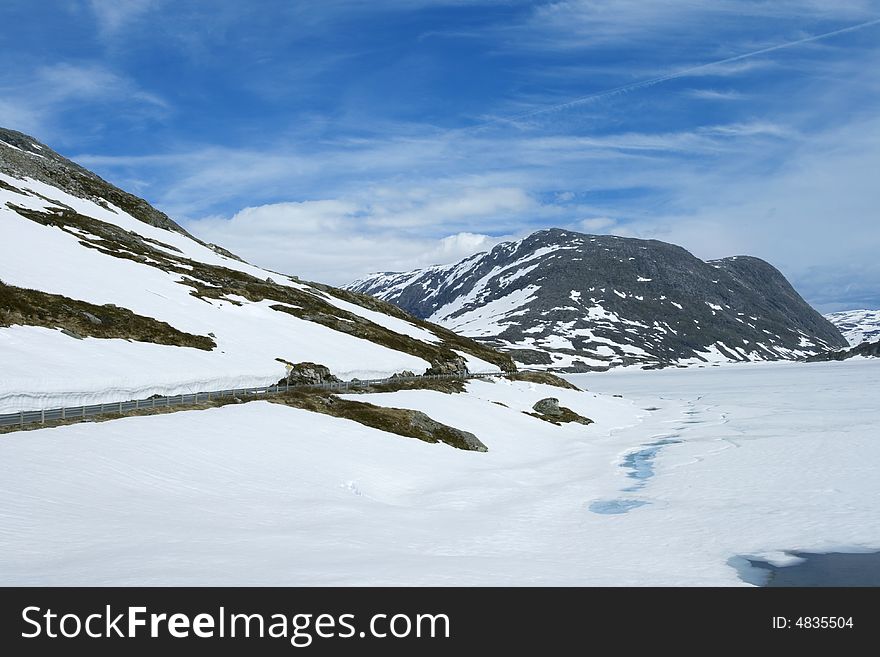 Road way along the snowing lake and rock, summer