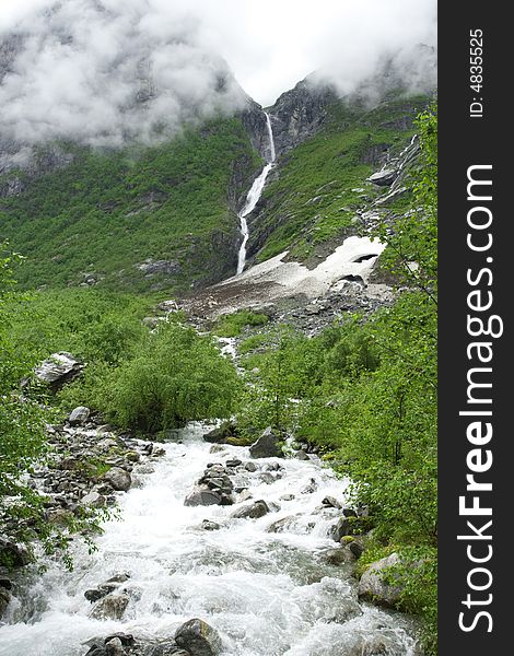 Raging river among the rocks, waterfall, fog, cloudy